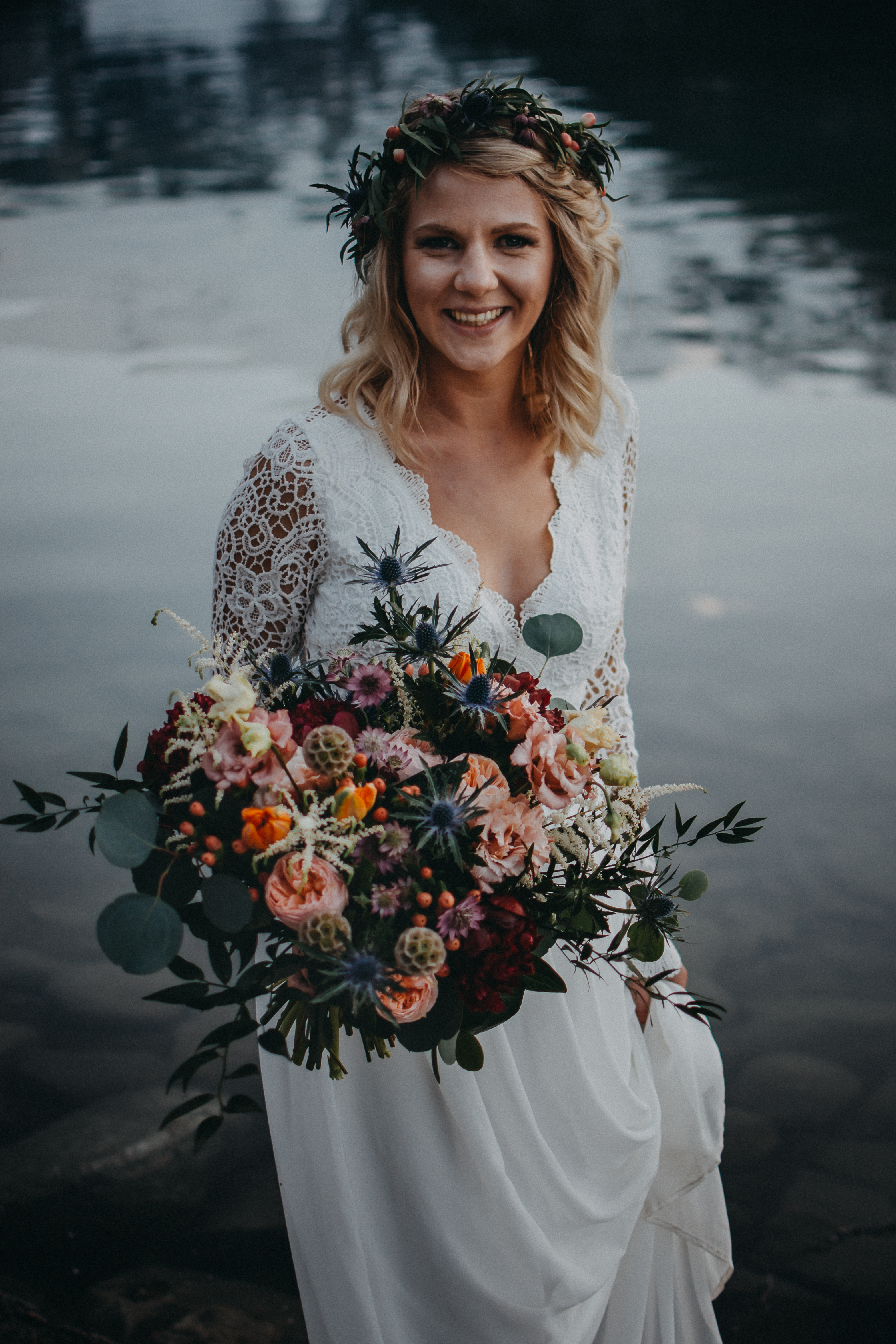 The bride holding her floral bouquet smiling at the camera at Lake Louise, Alberta
