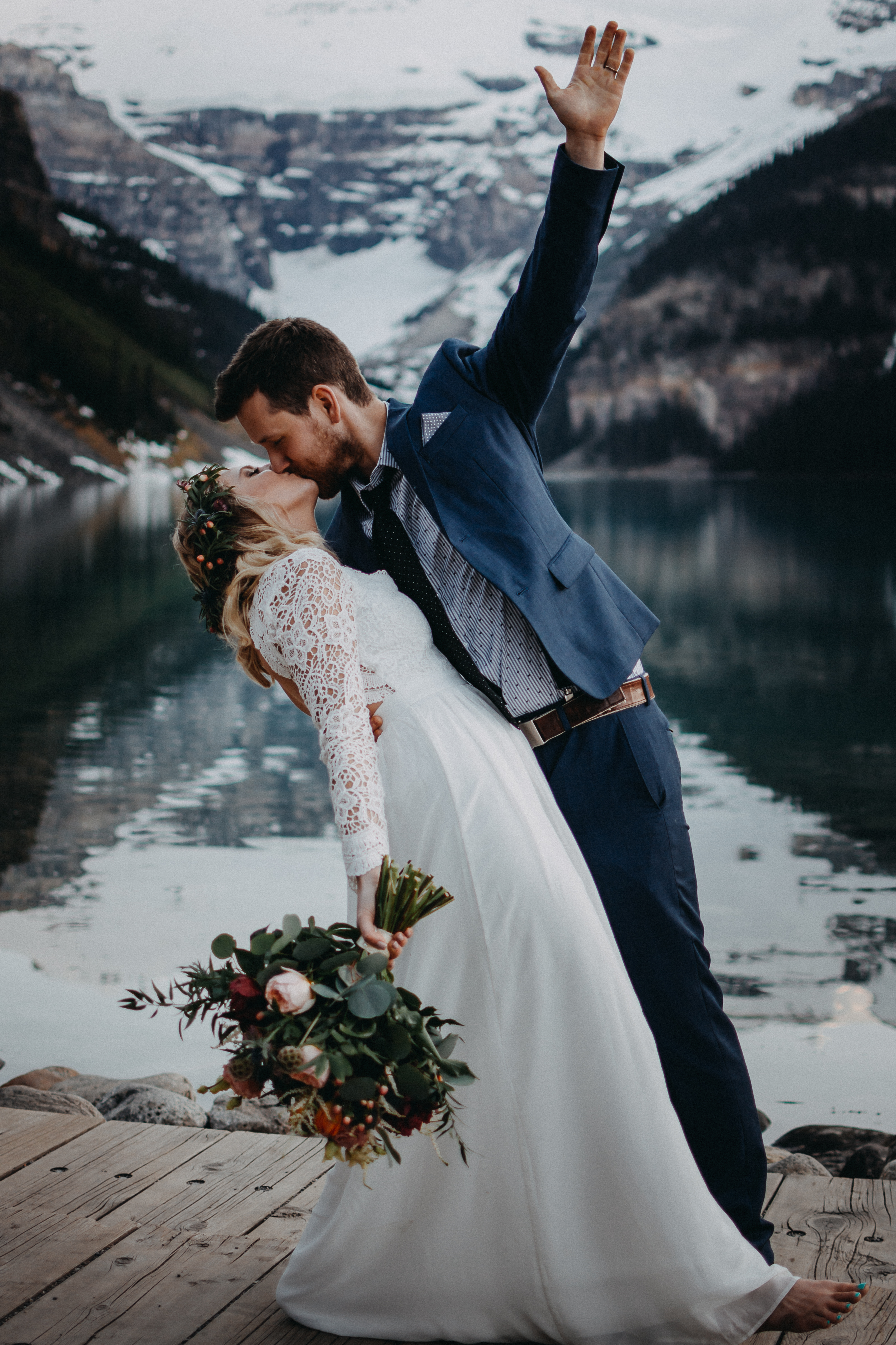 The groom dipping the bride and throwing his hand up in the air at Lake Louise, Alberta