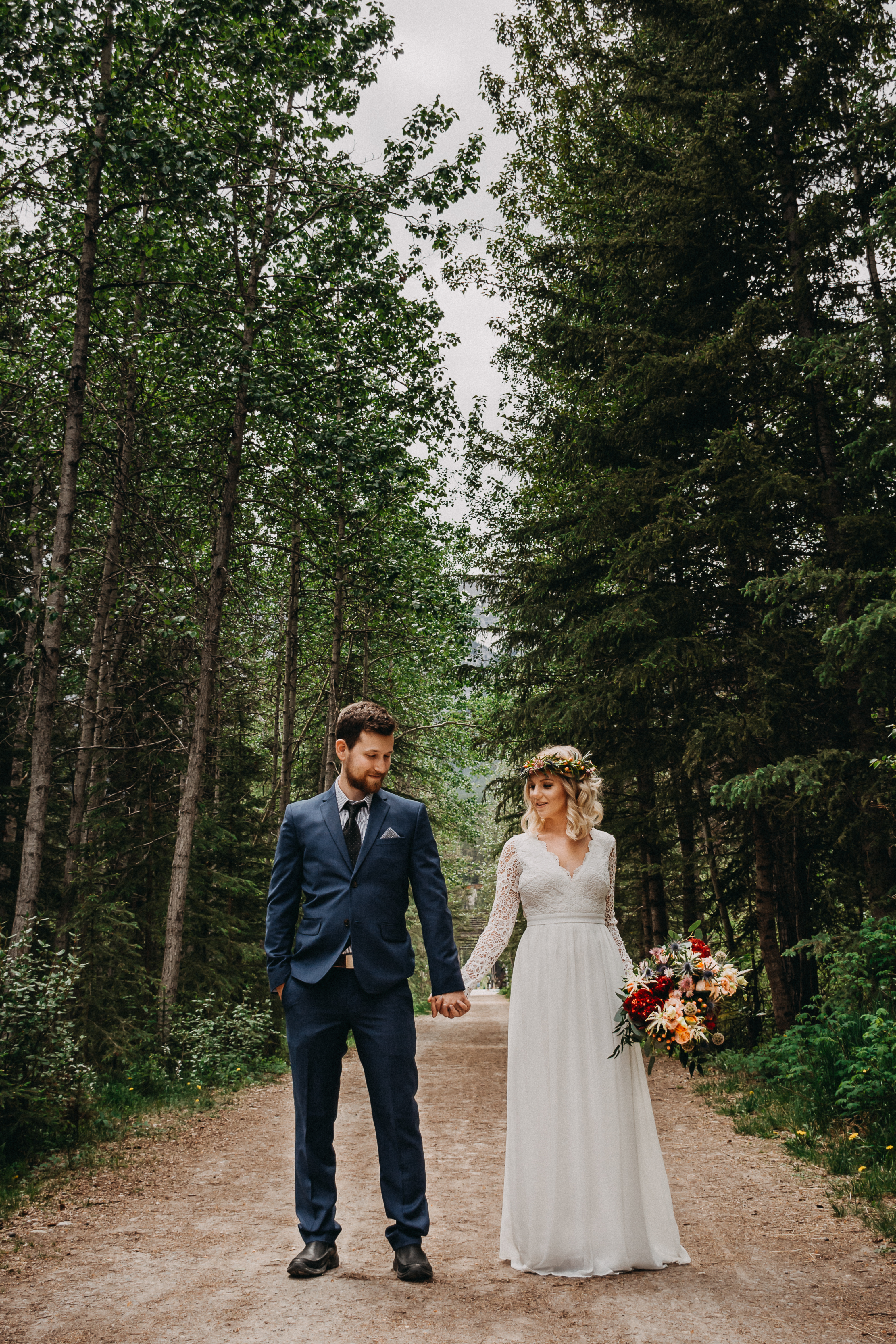 Groom and Bride standing in the woods, holding hands