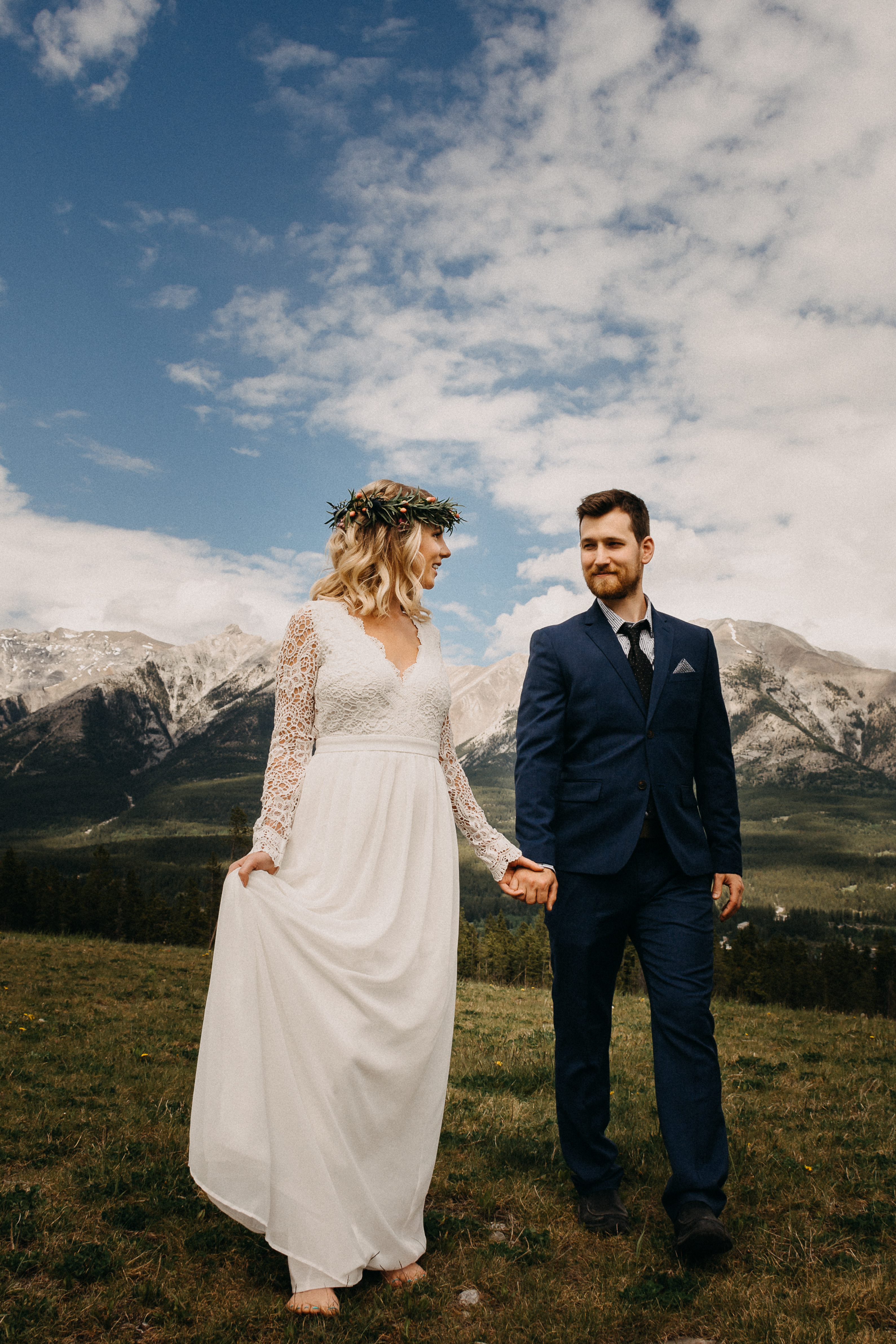 The bride and groom holding hands and looking at each other in front of the rocky mountains