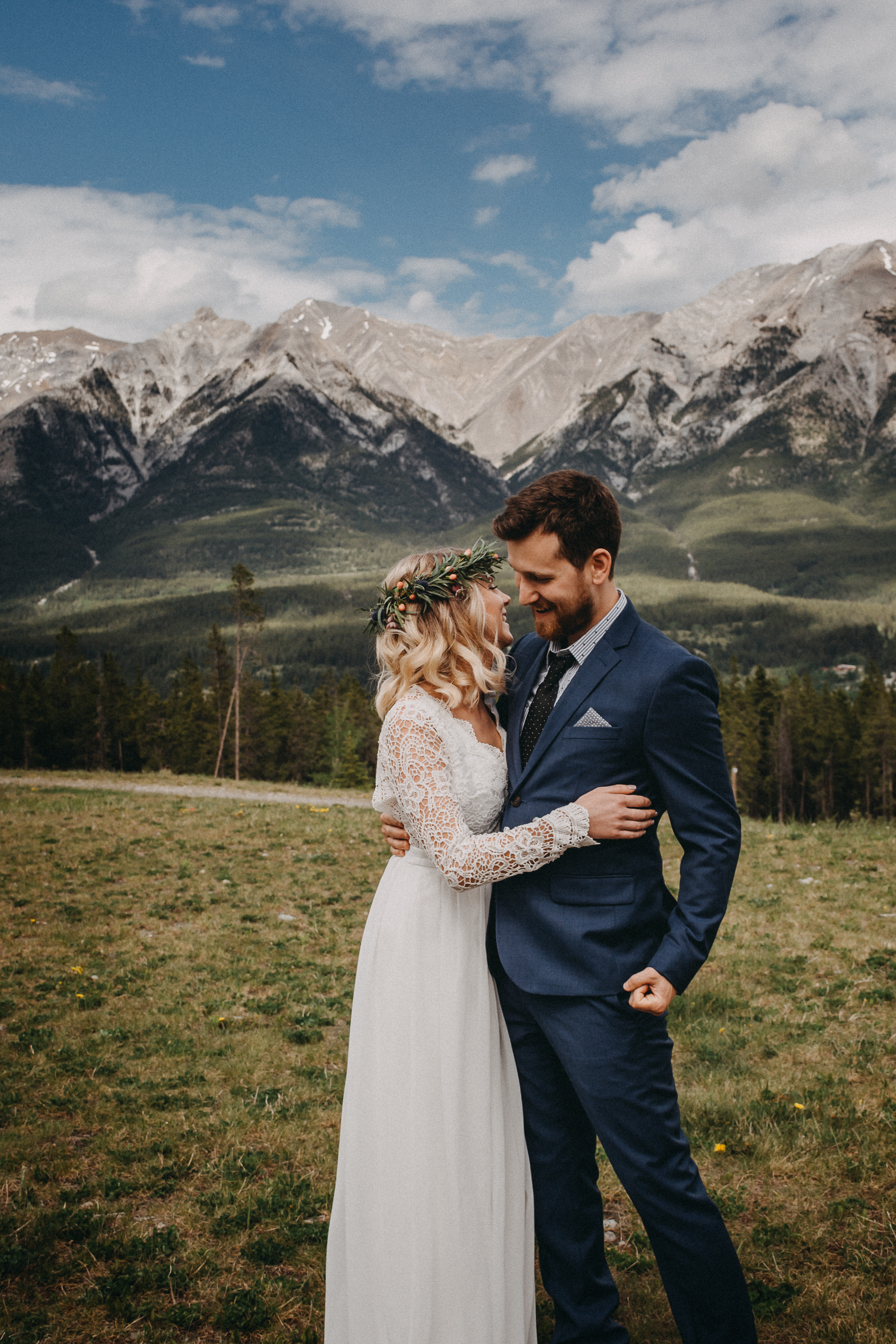 The bride and groom holding each other and laughing in front of the rocky mountains