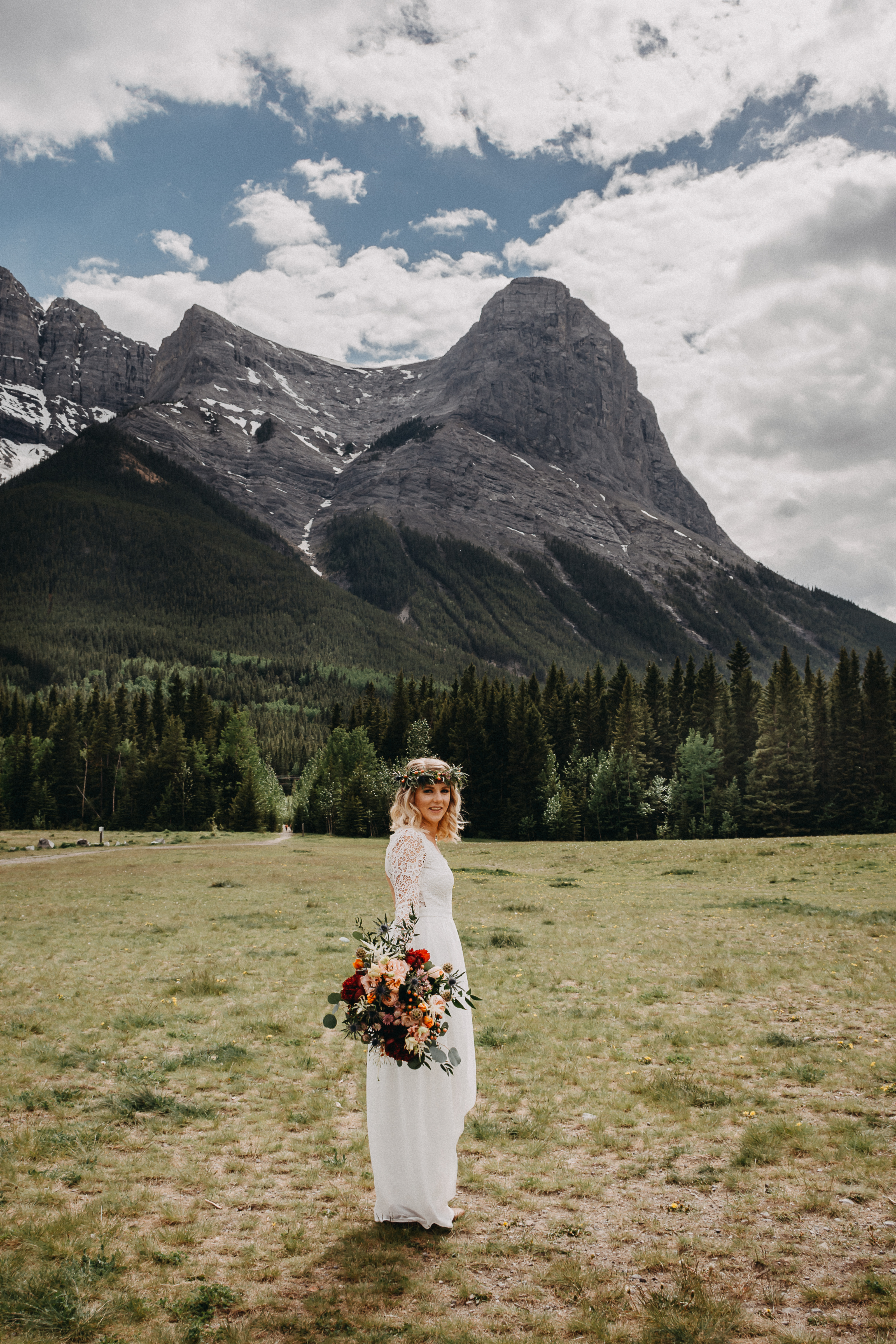The bride posing in front of the rocky mountains with her floral bouquet