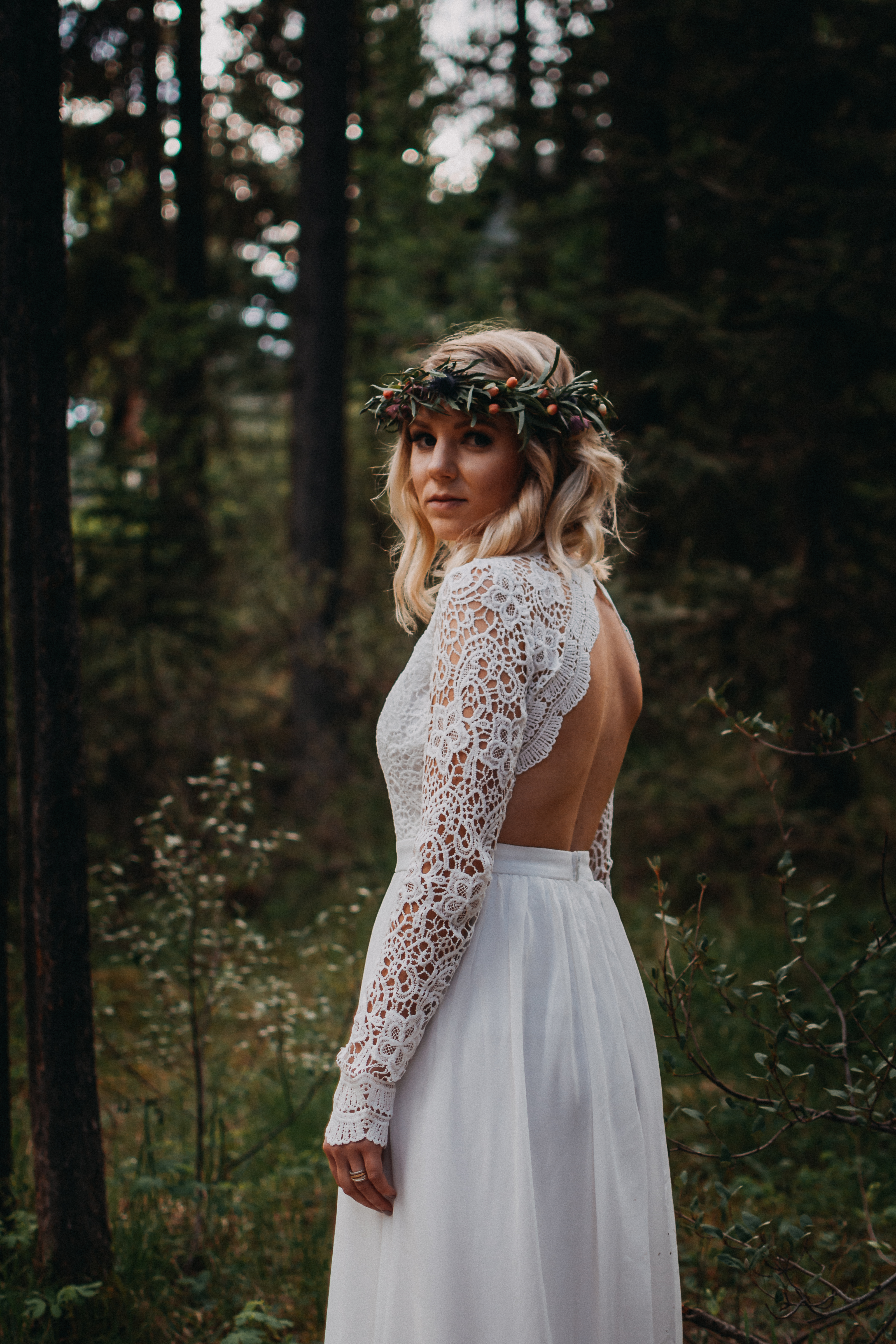 The bride posing in a forest looking at the camera, wearing a floral crown