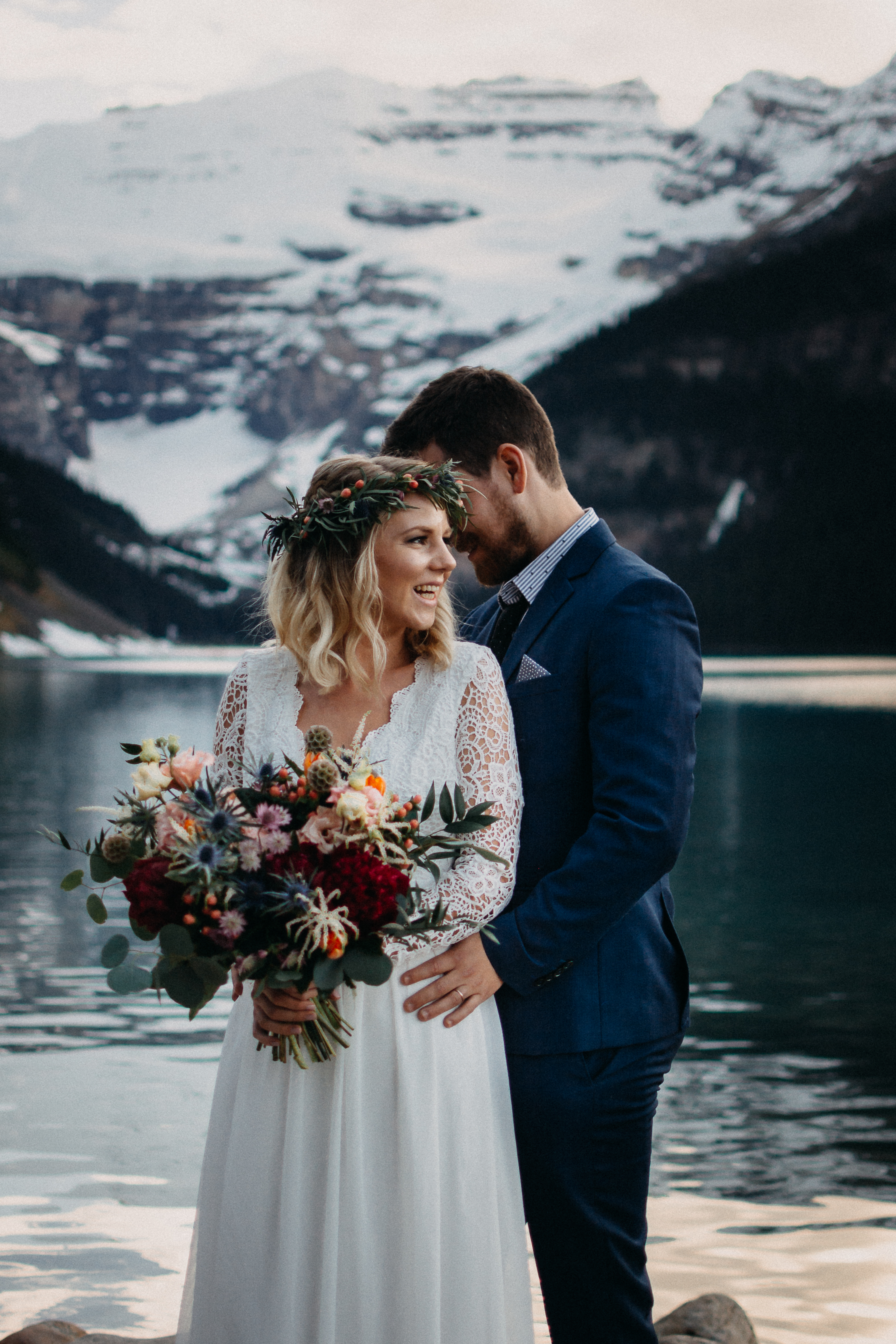 The bride laughing and groom holding each her at Lake Louise, Alberta