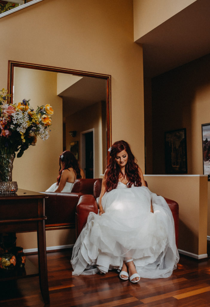 bride sitting in chair in front of a big mirror