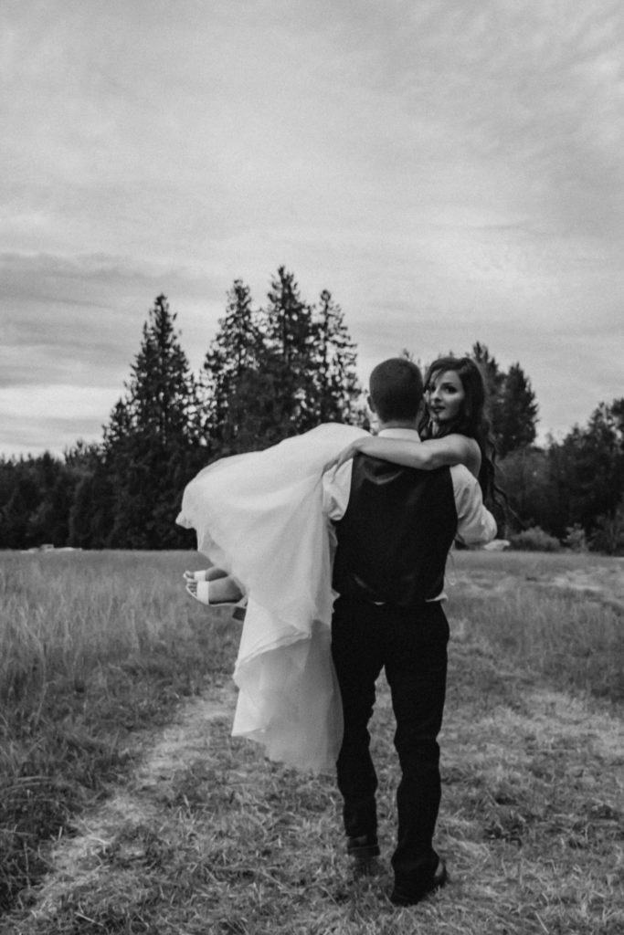 groom holding bride walking off towards a forest, black and white image
