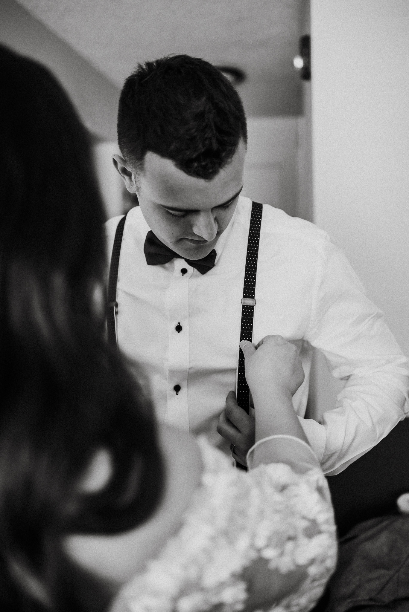 Bride helping groom with suspenders at Coast Canmore Hotel, Alberta