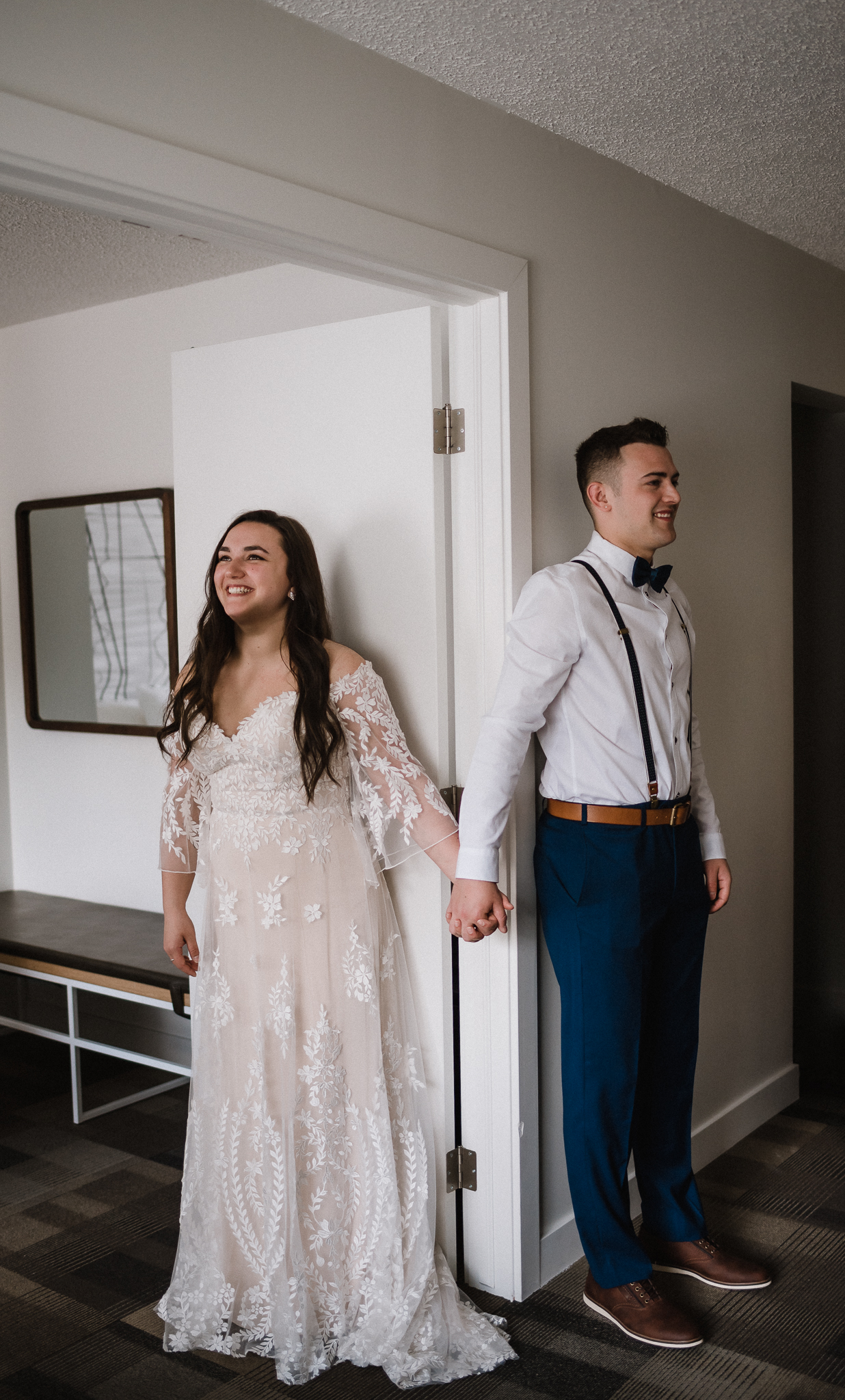 Bride and groom holding hands in front of door at Coast Canmore Hotel, Alberta