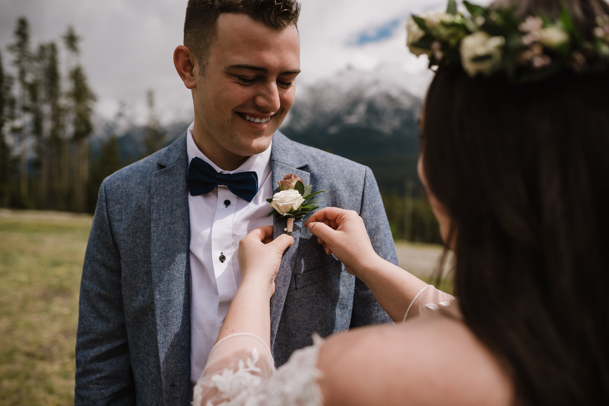 Bride pinning the corsage on groom at Nordic Center, Canmore