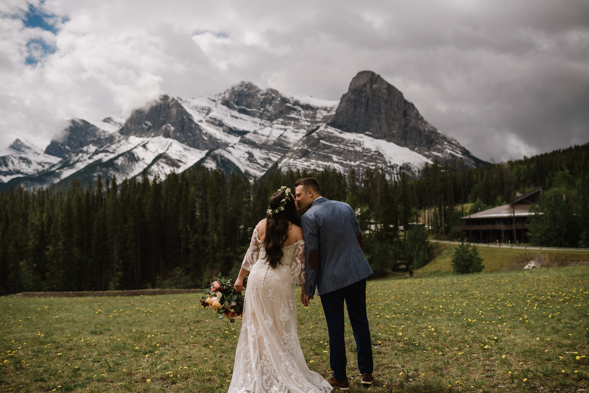 Bride and groom kissing with a mountain backdrop at the Nordic Center, Canmore