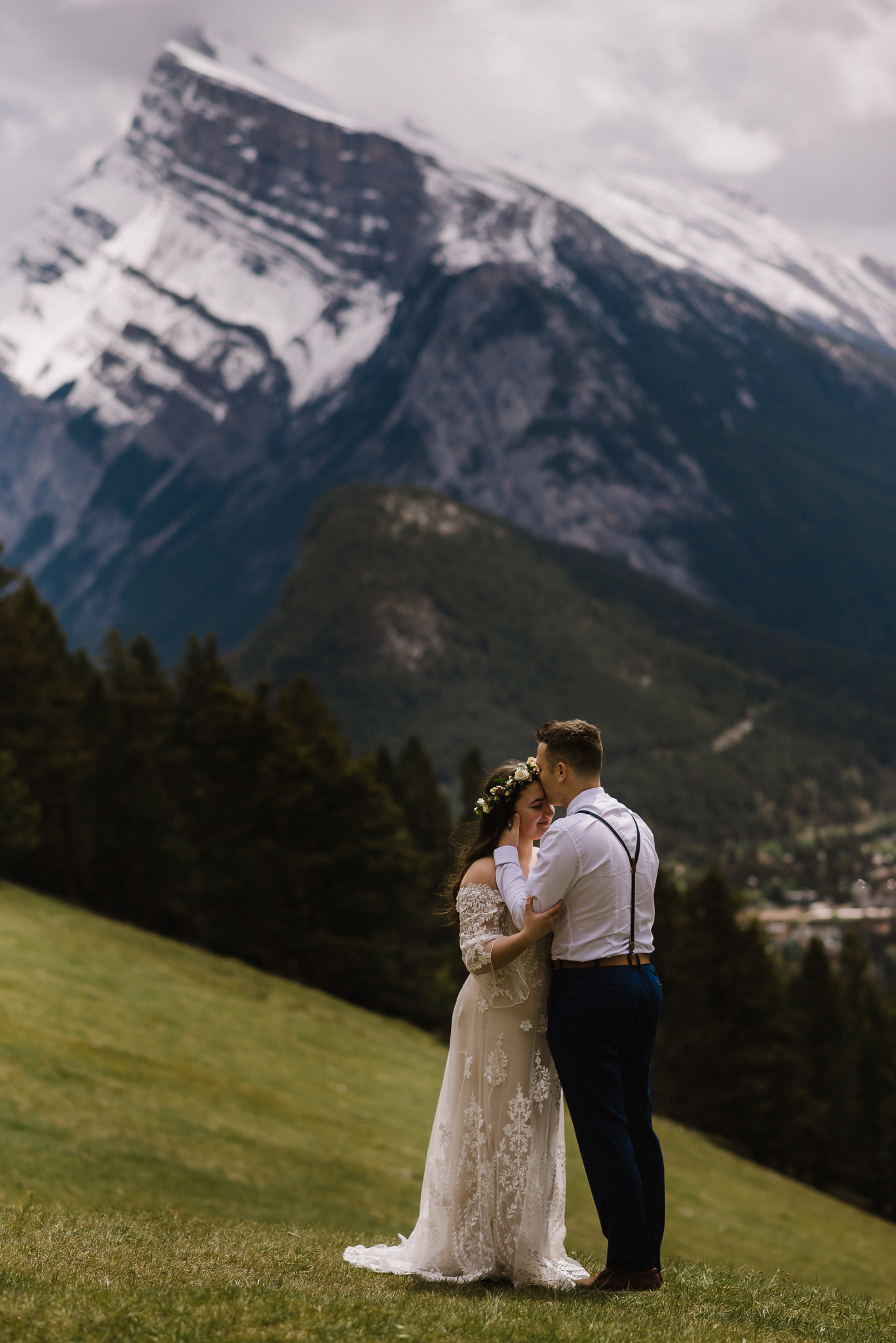 Groom kissing bride on forehead at Mount Norquay Lookout, Banff