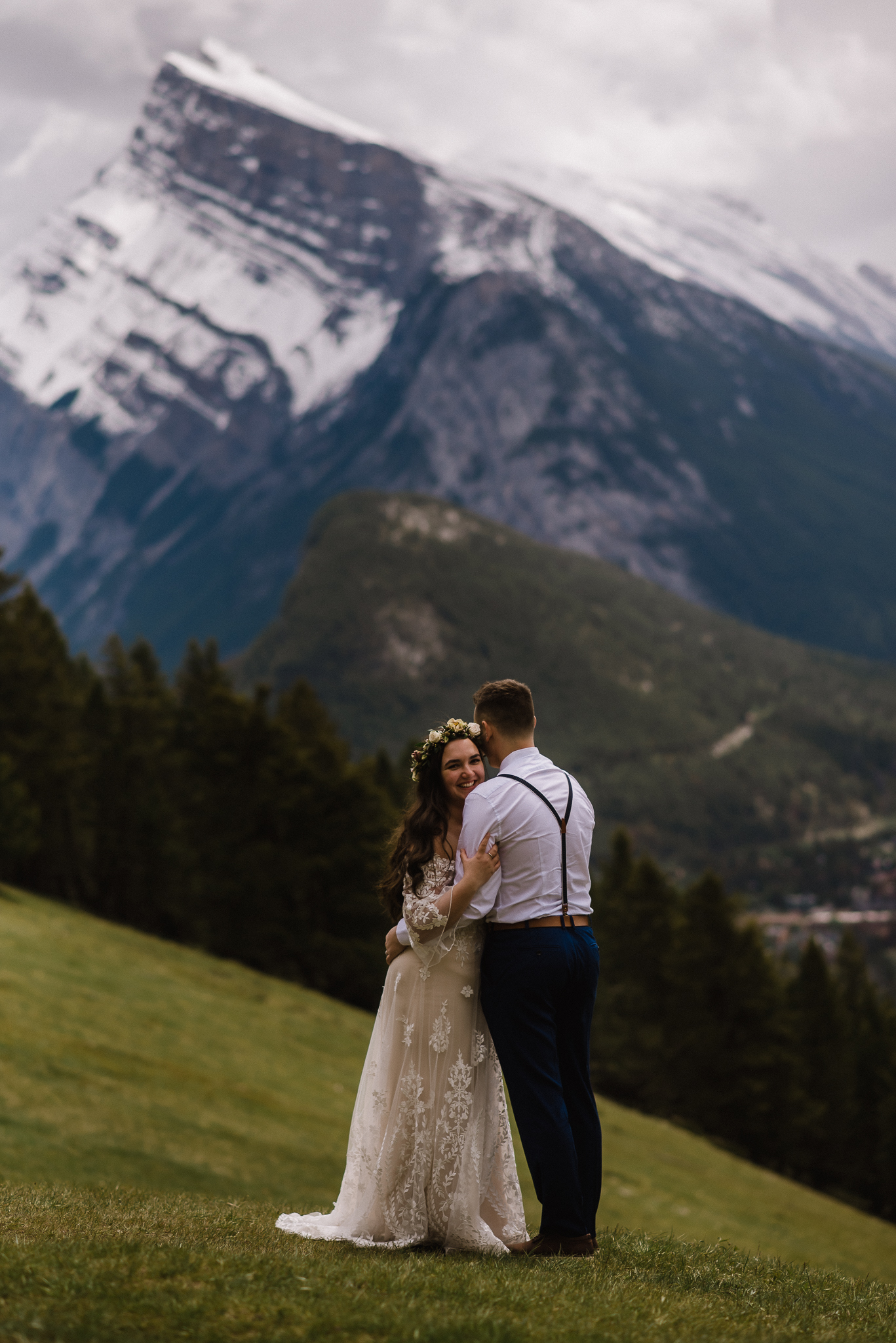 Groom and bride hugging while bride smiles at Mount Norquay Lookout, Banff