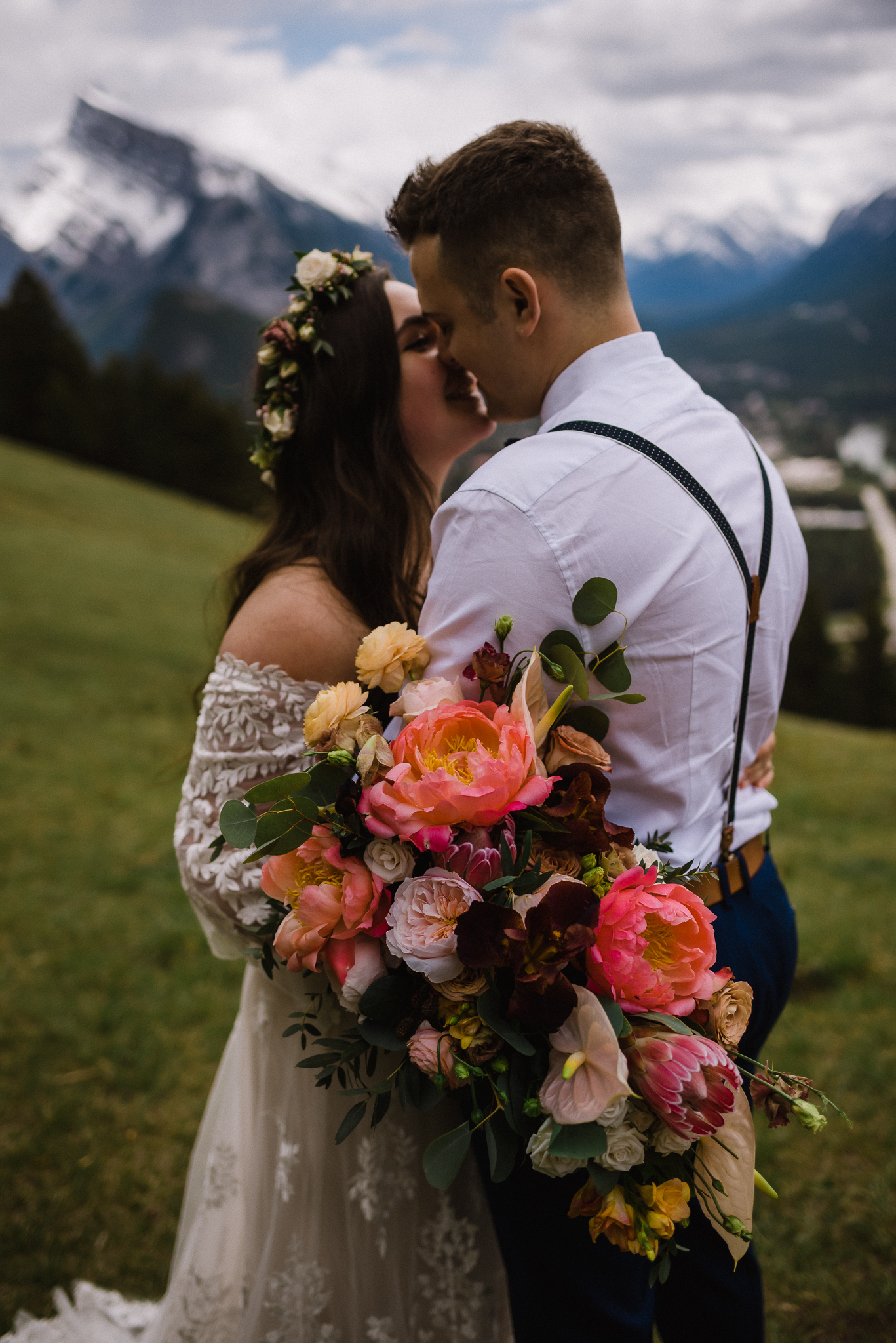 Close up of bride and groom kissing while she holds bouquet at Mount Norquay Lookout, Banff