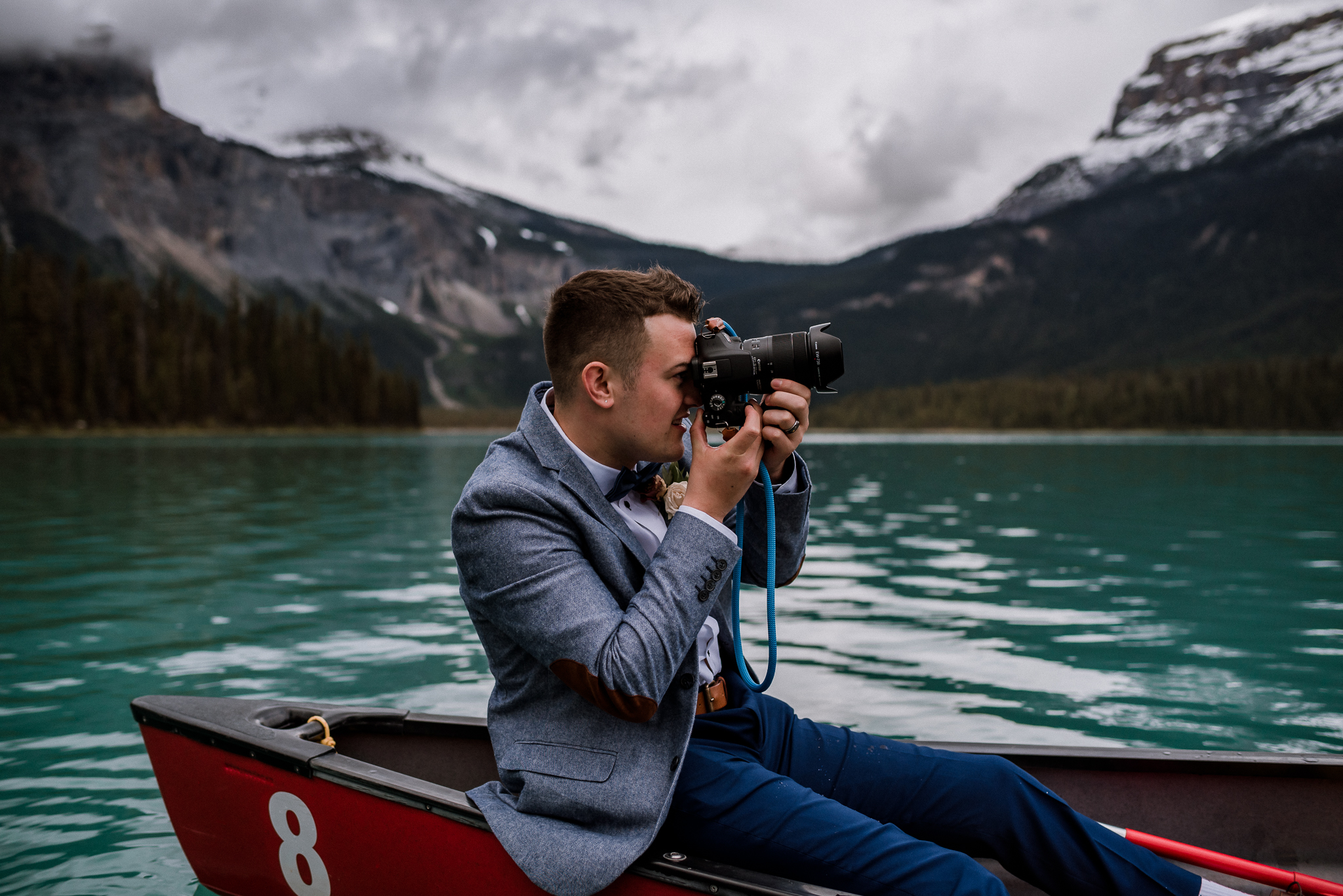 Groom taking a picture in red canoe at Emerald Lake, BC