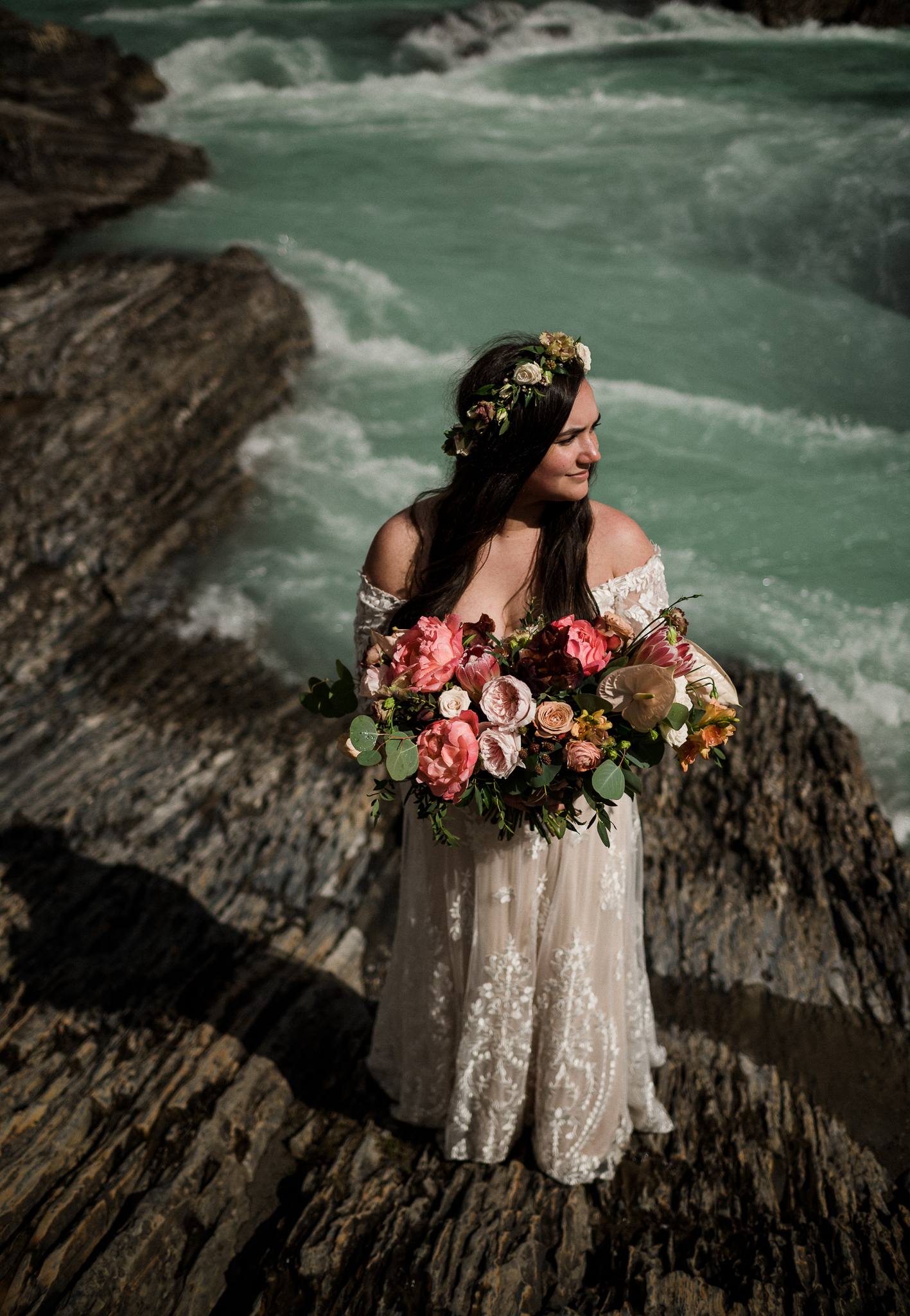 Bride holding beautiful bouquet in front of river at Yoho National Park