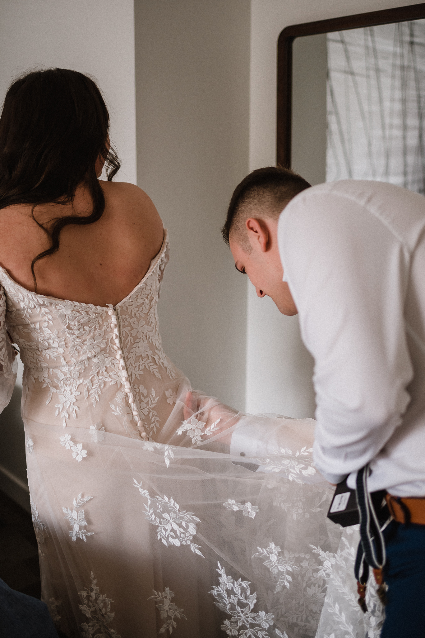 Groom helping bride with dress at Coast Canmore Hotel, Alberta