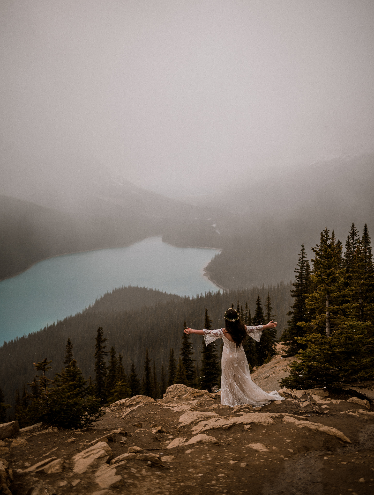 Bride standing on top of mountain with arms open at Peyto Lake, Alberta