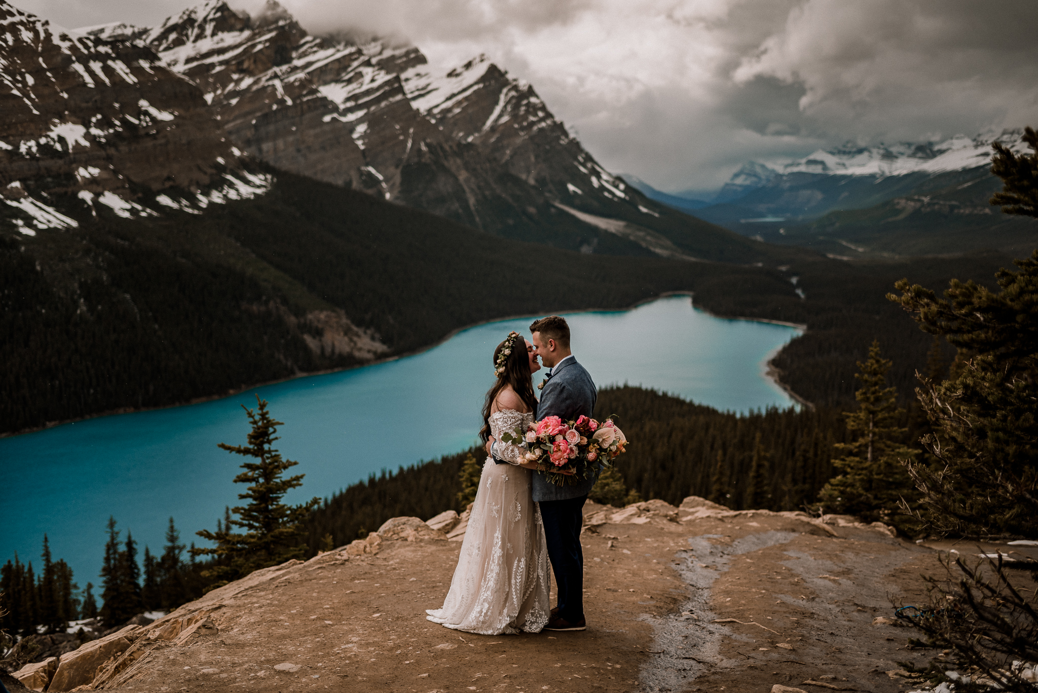 Bride and groom holding each other with bouquet at Peyto Lake, Alberta