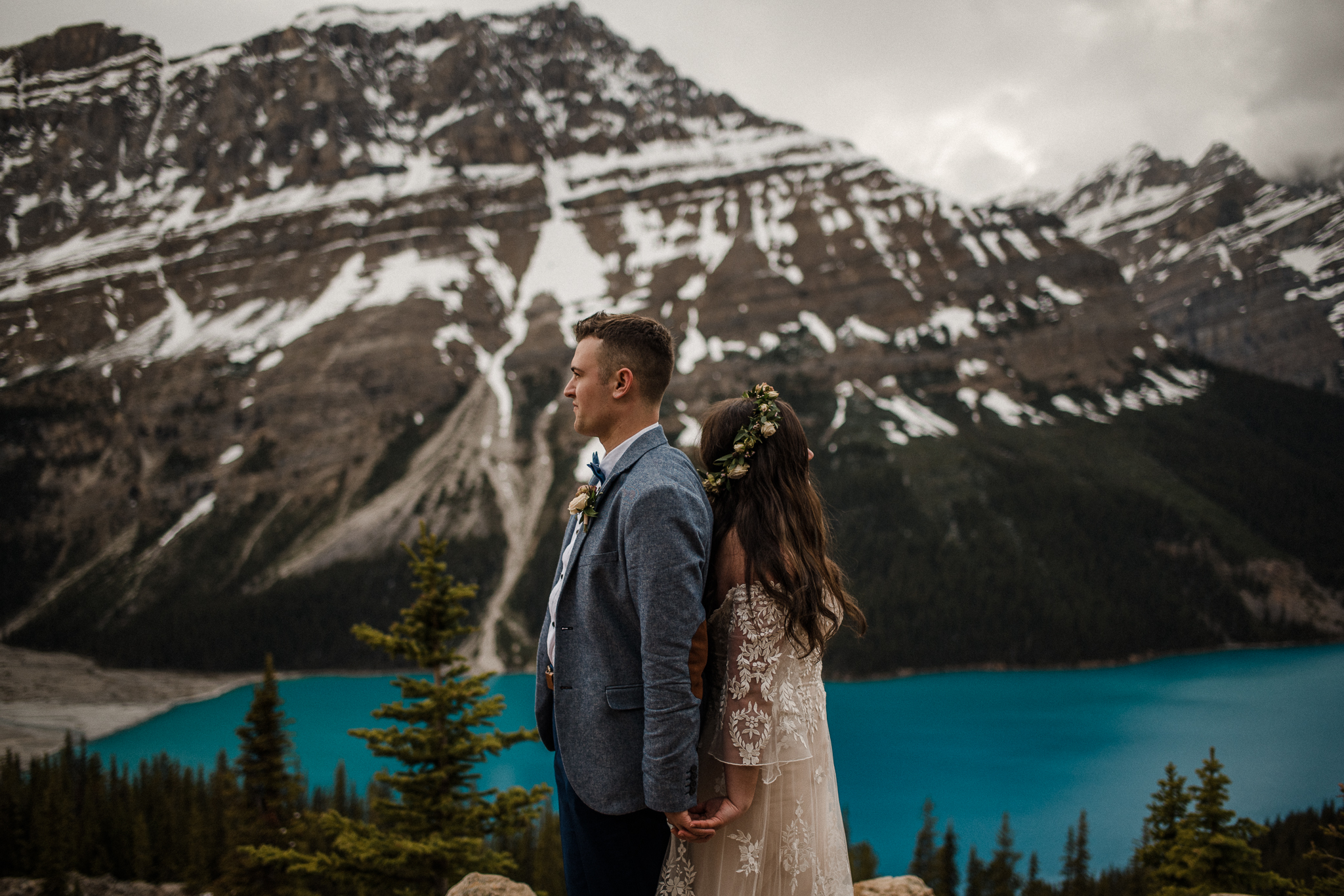 Bride and groom holding hands back to back looking away in front of Peyto Lake, Alberta