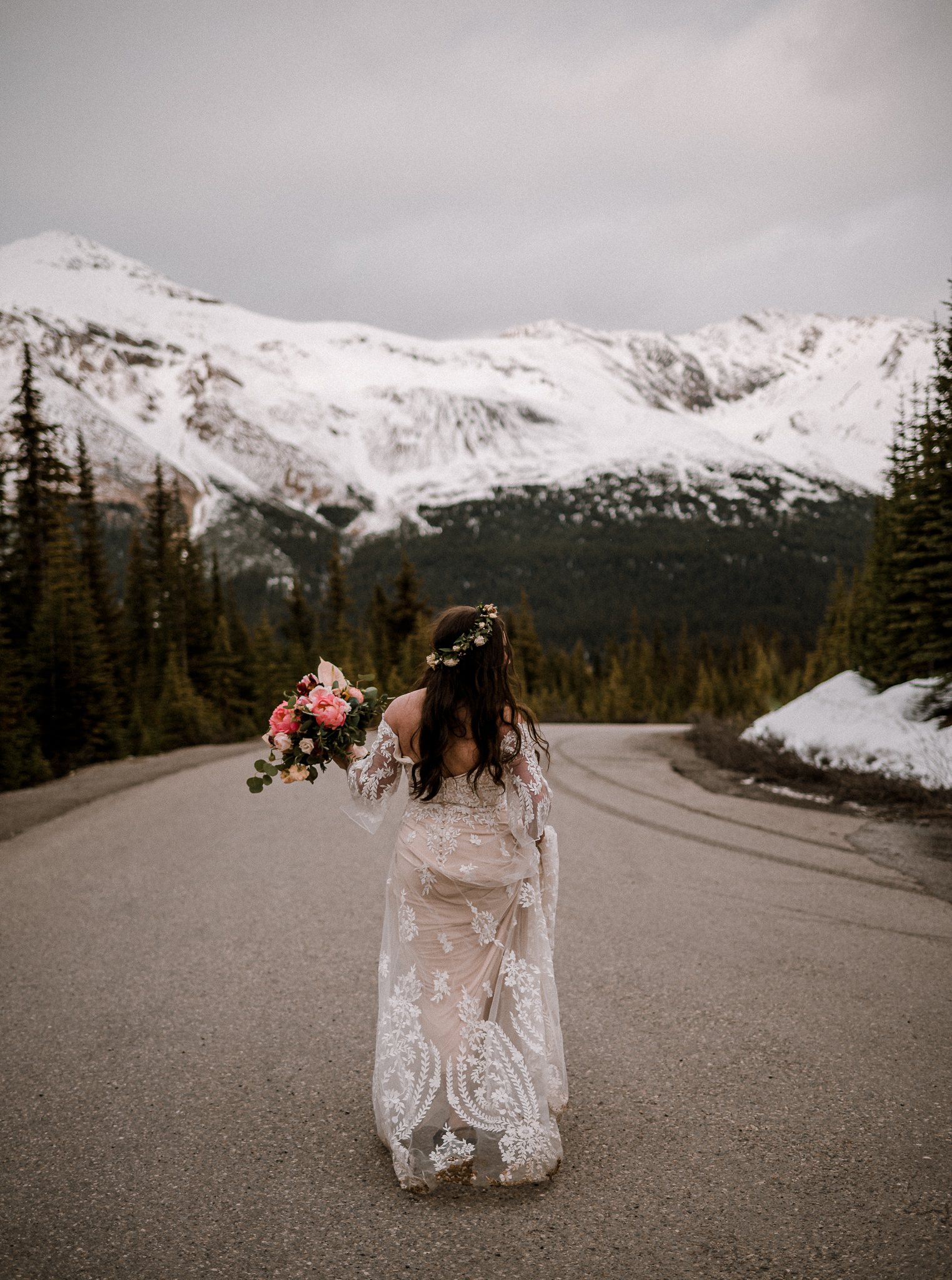 Bride holding bouquet walking away down an empty road