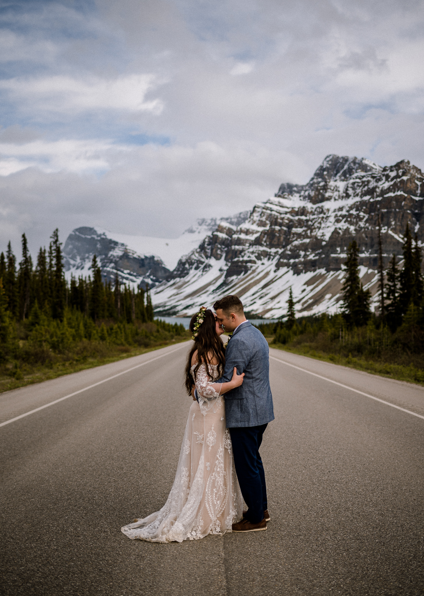 Bride and Groom kissing on empty road in front of mountains in Alberta