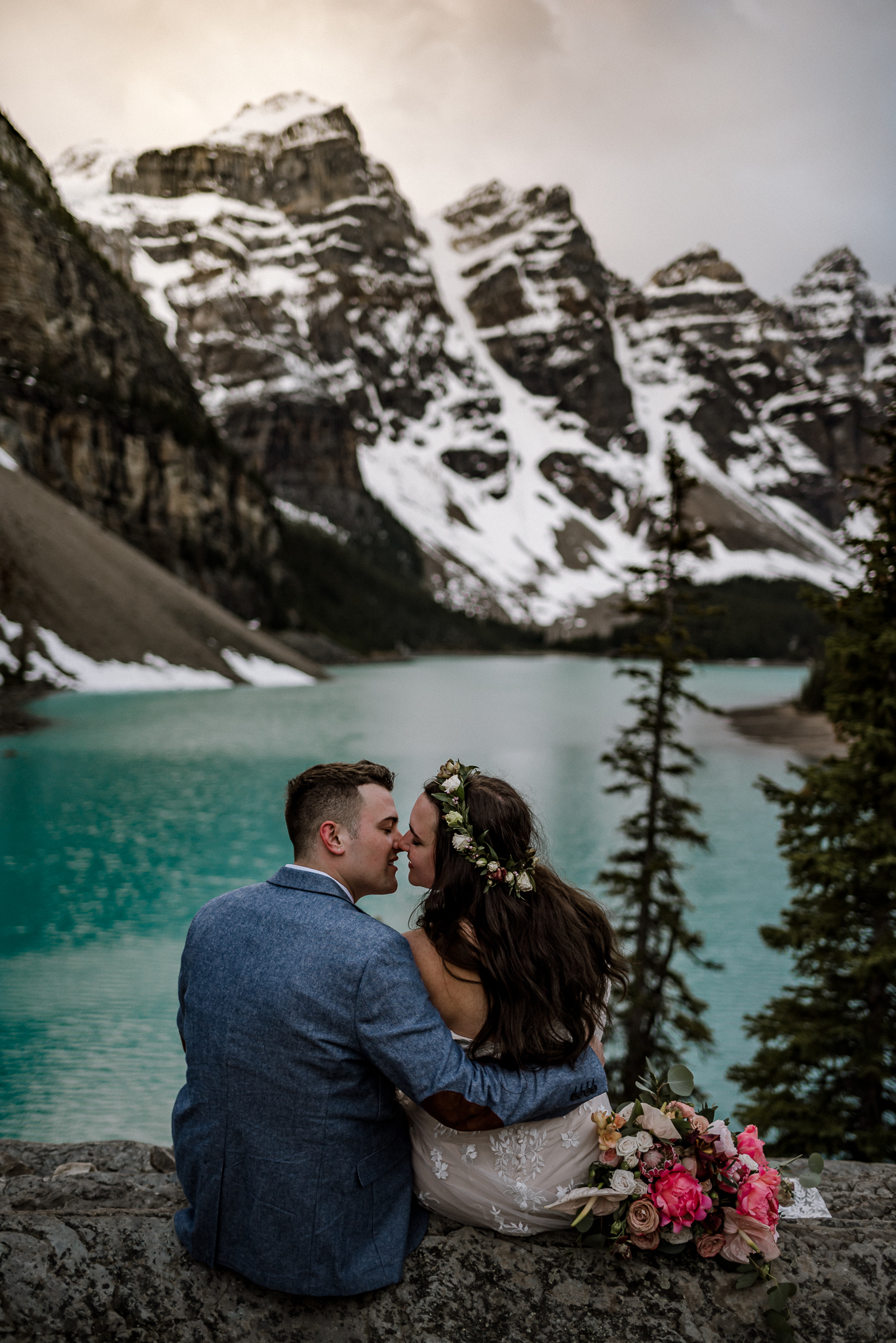 Close up of groom and bride almost kissing sitting on a rock at Moraine Lake, Alberta