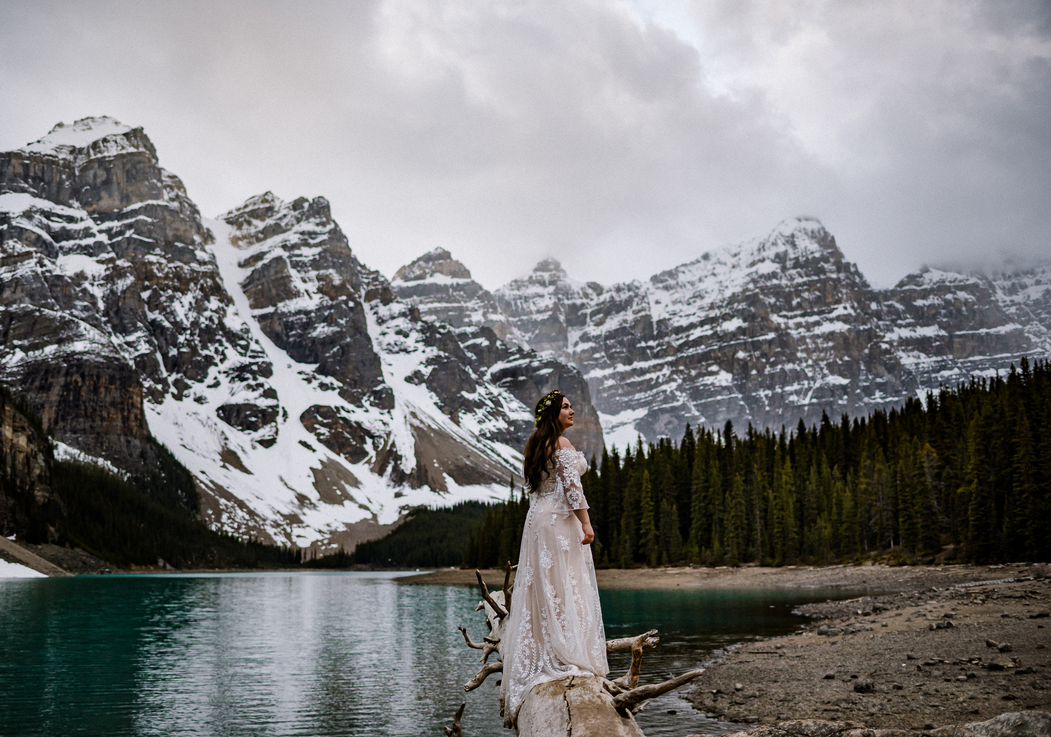 Beautiful bride standing on log at Moraine Lake, Alberta