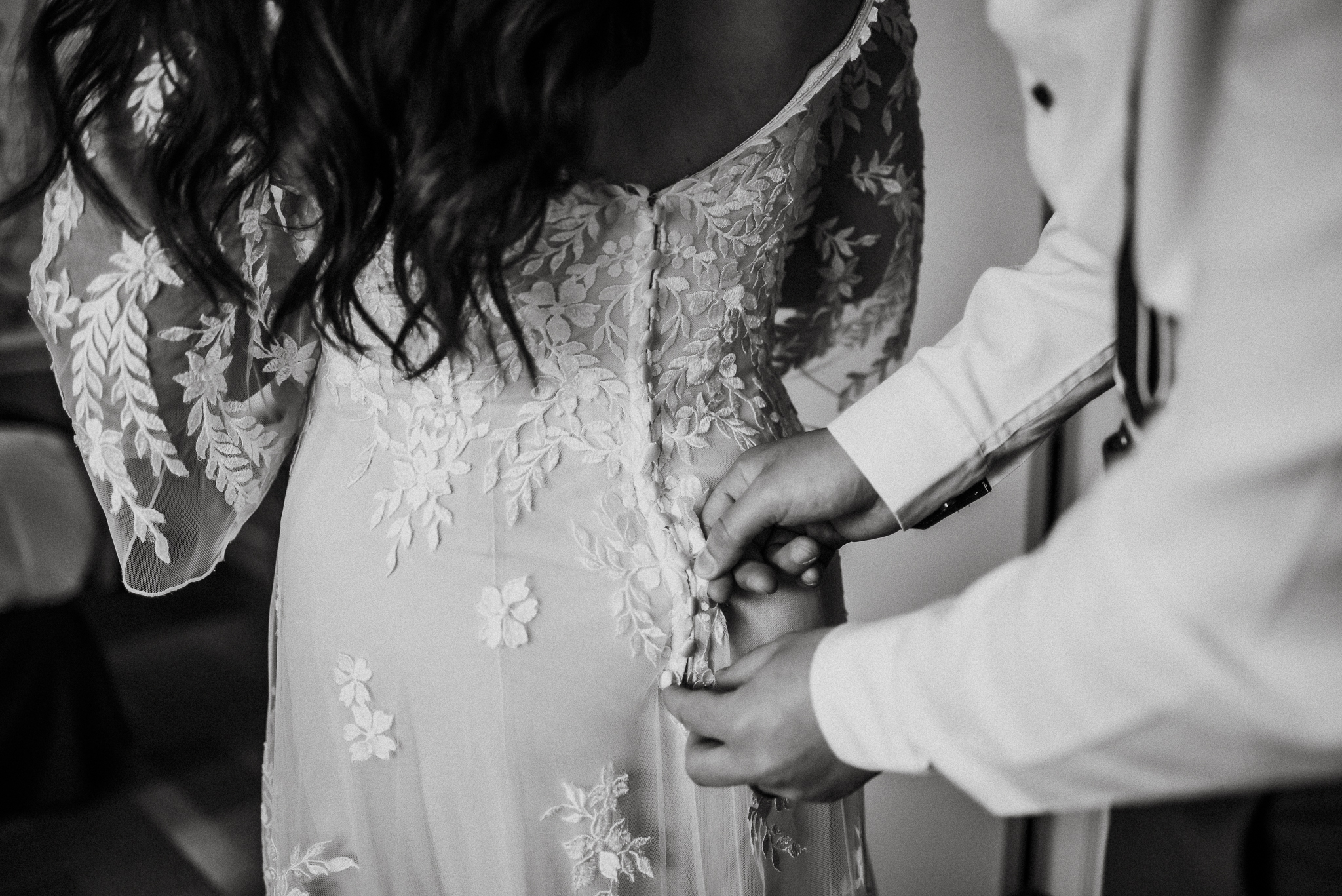 Groom helping bride with buttons on dress at Coast Canmore Hotel, Alberta